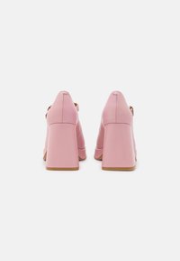Roze schoenen met hak, met een glad leren afwerking, een ronde neus en een blokhak. Voorzien van een achterriem en subtiele stikdetails.