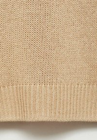 Pulover tricotat de culoare bej deschis, cu un design texturat. Baza ribbsată cu un finisaj neted, evidențiind cusături uniforme pe tot parcursul.