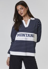 Polo a righe navy e bianche con scollatura a V e branding "MONTANA USA" sul petto. Realizzato in morbido cotone.