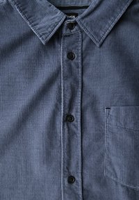Blue corduroy shirt featuring a pointed collar, button-down front, and a single chest pocket with vertical ribbed texture.