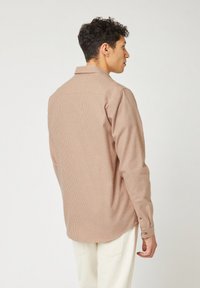 Camicia a righe con bottoni in tonalità beige e marrone chiaro, dotata di colletto, maniche lunghe e un design dalla vestibilità comoda. Tessuto testurizzato con linee sottili.