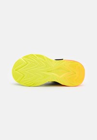 Black athletic shoe sole with a zigzag tread pattern. Bright yellow with orange accents, featuring "SKECHERS" branding.