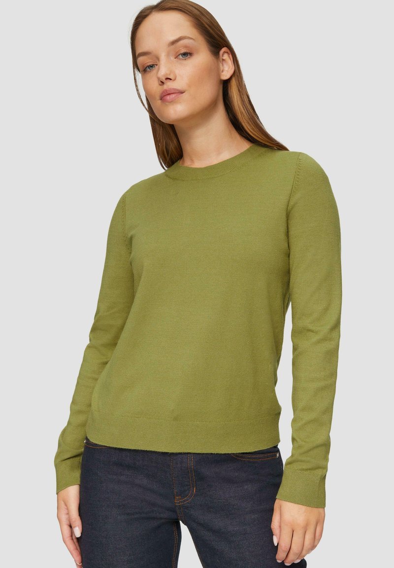Grüner Strickpullover mit rundem Ausschnitt und langen Ärmeln, mit weicher Textur und gerippten Bündchen, getragen über dunkler Jeans.