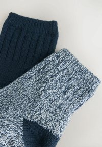 Skarpety robione na drutach z ciemnoniebieskim ściągaczem i jasnoniebieską, melanżową cholewką z fakturowym wzorem oraz kontrastującą końcówką.