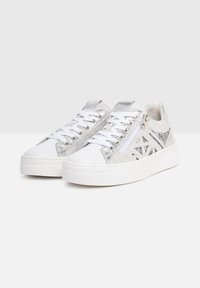 Białe sneakersy z srebrnymi akcentami z brokatu oraz bocznym zamkiem. Posiadają płaską podeszwę, okrągły czubek i teksturowany materiał na dekoracyjnych panelach.