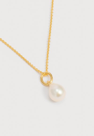Χρυσό κολιέ με αλυσίδα και μονό λευκό στρογγυλό μαργαριτάρι ως μενταγιόν, κρεμασμένο με μικρό χρυσό κρίκο σε απλό φόντο.