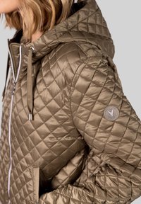 Quiltet pufferjakke i afdæmpet olivengrøn, med lynlås foran, hætte og subtilt logo-patch på ærmet, lavet af glat, shiny stof.