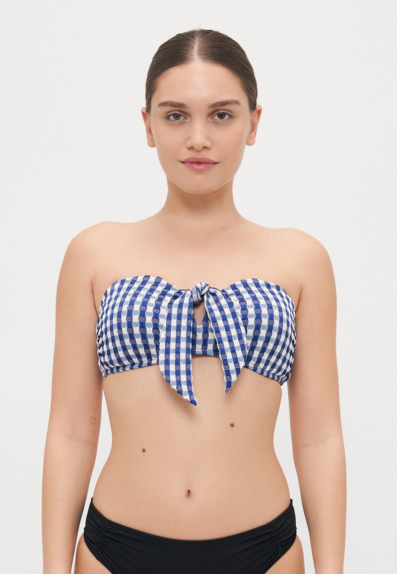 Mėlynos ir baltos plytelės rašto bandeau bikini viršus su priekine juosta, pasižymintis raktų angos išpjova ir tekstūruota medžiaga. Derinamas su juodais apatiniais.