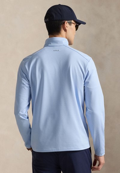 Ανοιχτό μπλε πόλο μπλουζάκι με μακριά μανίκια, ψηλό γιακά και ριμπ υφή. Διαθέτει κεντημένο λογότυπο στο πίσω μέρος και άνετη εφαρμογή.