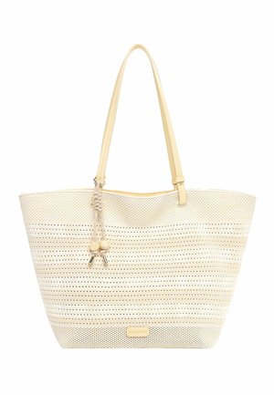 Sac fourre-tout beige perforé avec de longues anses et des pompons décoratifs, avec une étiquette de marque subtile près du bas.