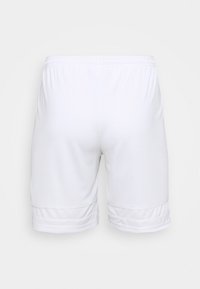 Pantalones cortos deportivos blancos con cinturilla elástica y un sutil detalle de costura cerca del dobladillo, vistos desde atrás sobre un fondo liso.