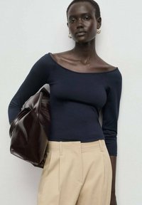 Námornícky off-shoulder dlhý rukáv top v priliehavom dizajne, doplnený béžovými nohavicami s vysokým pásom a tmavohnedou kabelkou.