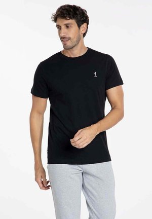 T-shirt en coton noir avec un col rond, des manches courtes et un petit logo brodé sur la poitrine, associé à un jogging gris.