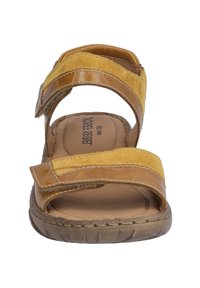 Brown leather sandal with yellow suede straps, adjustable hook-and-loop fasteners, a cushioned footbed, and textured rubber outsole.