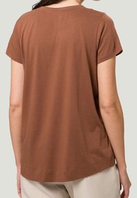 Brun kortærmet T-shirt lavet af blødt stof; afslappet pasform med rund halsudskæring og let buet kant. Glat tekstur, ingen synlige mønstre.