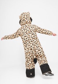 Leopardmönstrad snOverall i beige med orange detaljer, försett med en fluffig huva, svans och svarta vattentäta manschetter, designad för värme och komfort.