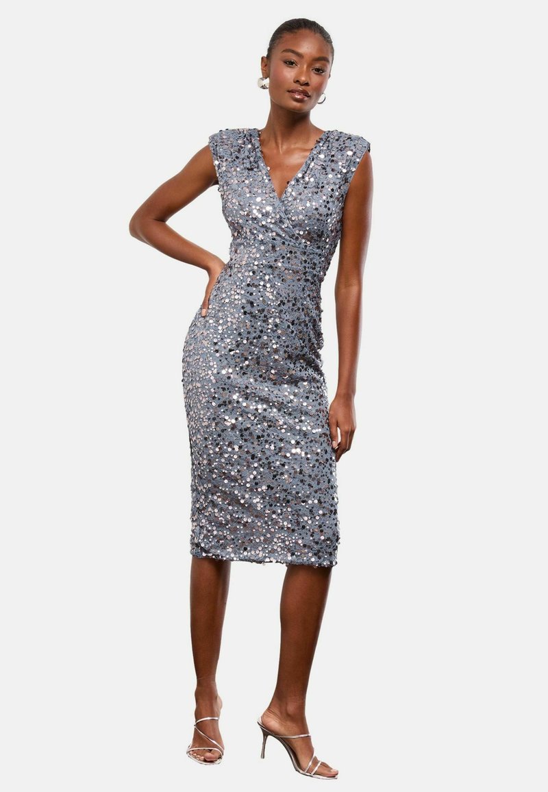 Szürke, testhez simuló ruha flitterekkel borítva, V-kivágással és kis ujjakkal, térd alá érő szegéllyel és karcsú sziluettel.