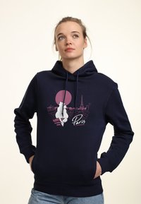 Marinblå hoodie med en framsida som visar en silhuett mot en rosa sol och Paris skyline. Har dragsko och en känguruficka.