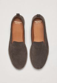 Zapatos de ante marrón tipo slip-on con una textura suave, bordeado cosido y un interior de cuero marrón, etiquetados "FRED MARTIN, HECHO EN ESPAÑA".