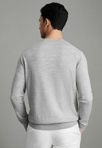 Pulover tricotat gri deschis, cu guler rotund, mâneci lungi și tiv cu bandă elastică. Textură moale, model ușor melanjat și siluetă ajustată.
