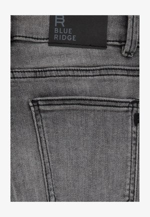 Grijze denim jeans met een klassiek vijf-pocket ontwerp, zichtbare stikdetails en een zwart leren label met de tekst "BLUE RIDGE."