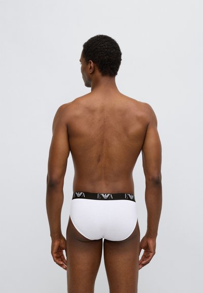 Mutandine bianche in cotone con elastico nero in vita con il logo "EVA" ripetuto a motivo. Presentano un design aderente e dettagli minimi.