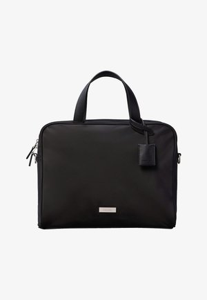 Črna aktovka Calvin Klein z dvema ročajema, sprednjo zadrgo in priloženim usnjenim obeskom, na belem ozadju.