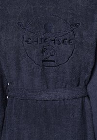 Navy-blaues Frottierbademantel mit strukturiertem Finish, Gürtel und gesticktem Logo mit einer Figur in einem kreisförmigen Design.
