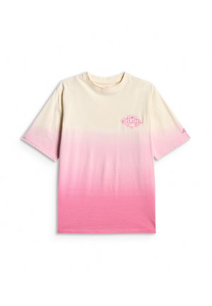 Uśmiechnięta dziewczynka z długimi ciemnymi włosami, ubrana w różowe legginsy, różowo-biały, dużych rozmiarów T-shirt ombre oraz białe trampki na szarym tle.