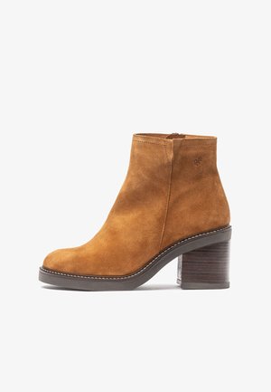 Suede ankle boot in brown with a rounded toe, side zipper, and wooden block heel. Features stitching along the sole and a smooth texture.