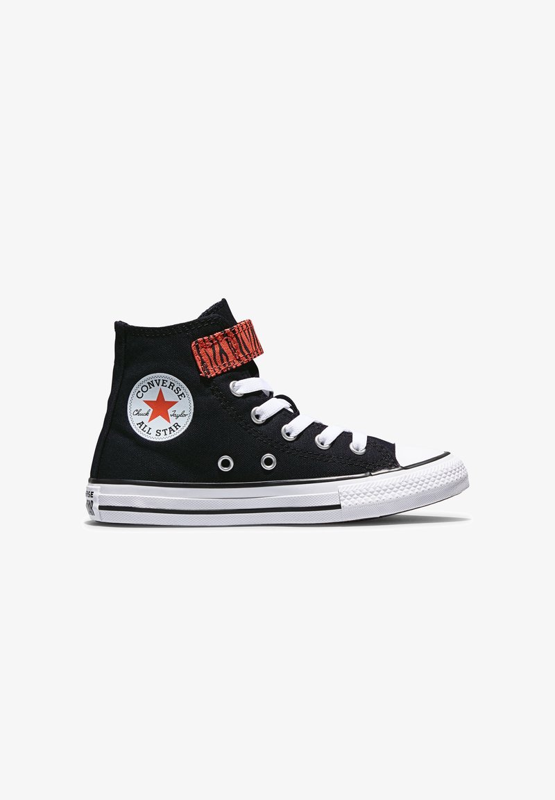 Basket Converse montante noire avec semelle blanche, lacets blancs, patch logo étoile rouge, et une sangle velcro rouge à motifs.
