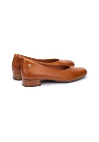 Ballerines en cuir marron avec un bout rond, un petit talon en bois et un subtil accent doré à l'arrière. Texture lisse et design minimal.