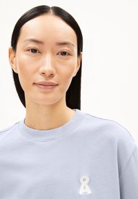 Lichtpaarse sweatshirt met een ronde hals, voorzien van een textuurwit logo op de borst. Glad, zacht materiaal met een comfortabele pasvorm.