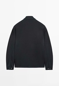 Czarna, długostanikowa koszula polo z prostym tyłem, miękką fakturą i zapinanymi mankietami. Posiada klasyczny kołnierzyk oraz minimalistyczny design.