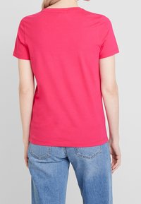Camiseta de algodón de manga corta en color rosa. Diseño simple de cuello redondo con una textura suave. Combinada con jeans de mezclilla azul claro.