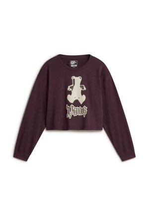 Langes lila Crop-Top mit langen Ärmeln, das ein Bärenmotiv und den Text "Vans" in heller Farbe zeigt. Aus Baumwolle gefertigt, mit glatter Textur und lässigem Schnitt.