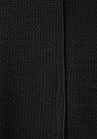 Tissu noir texturé présentant un motif tissé subtil, avec une couture lisse courant verticalement au centre.