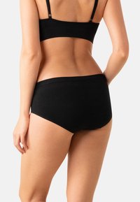 Sous-vêtements noirs en coton avec une texture douce, design taille basse et taille élastique, présentant des coutures minimales et sans logos visibles.