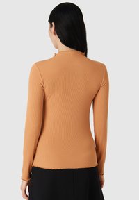 Maglia a maniche lunghe in morbido tessuto a coste, con scollatura rotonda e bordi arricciati. Colore: arancione caldo. Presenta una vestibilità slim e elasticità.