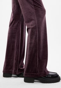 Βελούδινες φουστάνια σε σκούρο μωβ, με απαλό υλικό και φαρδιά γραμμή στα πόδια; συνδυασμένα με χοντρές μαύρες πλατφόρμες.