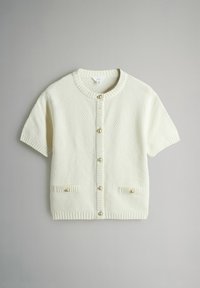Kremfarvet cardigan med korte ærmer i tekstureret strik, lukning med knapper foran, ribstrikkede kanter og to lommer med perlelignende knapper.