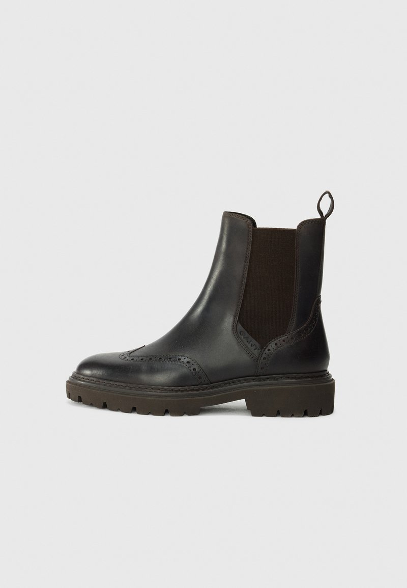 Mustad mustad n mudeliga Chelsea saapad elastsete külgdetailidega, brogue kaunistuse ja tumesinise kummeeritud tallaga. Tagumine aas mugavaks selga panemiseks.