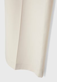 Rideau en tissu écru avec une légère texture et un pli vertical, suspendu devant un fond blanc.