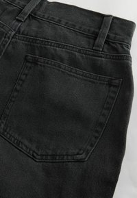 Svarta jeans i denim med detaljer som en bakficka med sömmar och texturerad tyg. Midjebandet har bältesöglor för accessoarer.