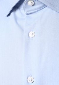 Hellblaues Hemd mit klassischem Kragen, zwei weißen Knöpfen und einem glatten, strukturierten Stoff mit einem subtilen Glanz.