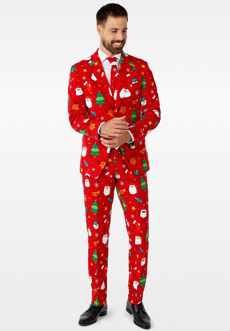 Costume rouge avec des motifs festifs de Père Noël, sapins de Noël et décorations ; coupe ajustée, avec cravate assortie et chaussures noires brillantes.