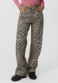 Pantalones de pierna ancha con estampado de leopardo, fabricados con un tejido suave, con una cintura alta, bolsillos frontales y un corte relajado. Acentuados con negro.
