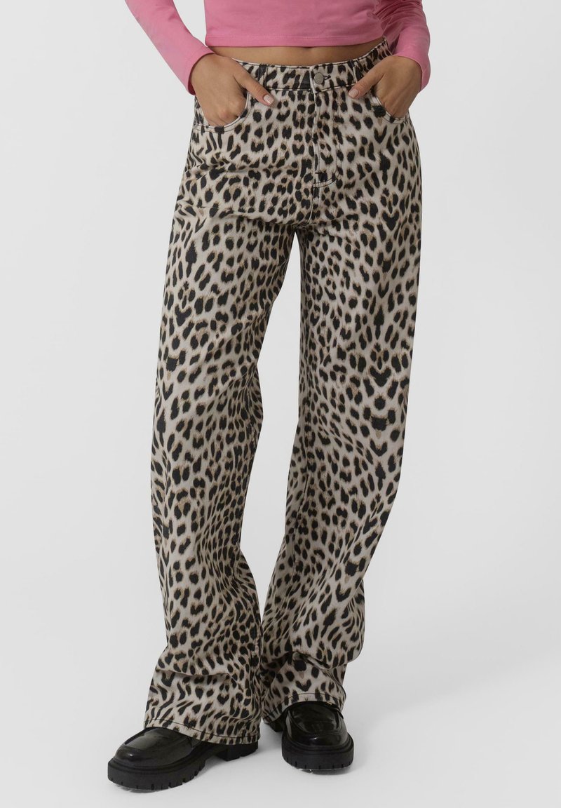 Pantalones de pierna ancha con estampado de leopardo, fabricados con un tejido suave, con una cintura alta, bolsillos frontales y un corte relajado. Acentuados con negro.