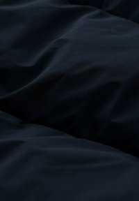 Tessuto strutturato di un blu navy scuro con pieghe morbide e superficie liscia, adatto per letti o applicazioni di tappezzeria.