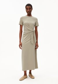 Knielanges, kurzärmeliges Kleid aus sanftem olivgrünem Stoff mit einem Frontknotendetail. Glatte Textur mit geradem Schnitt. Leicht.